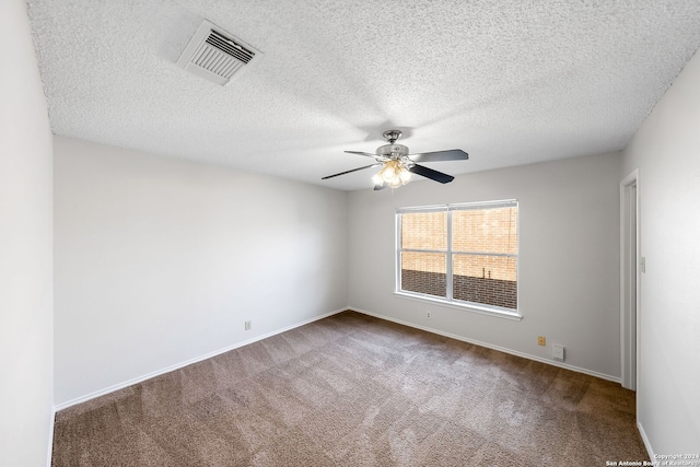 carpeted empty room featuring ceiling fan, a textured ceiling, visible vents, and baseboards