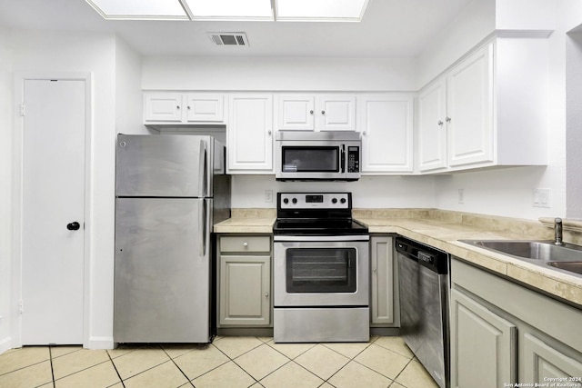 kitchen with light tile patterned floors, light countertops, appliances with stainless steel finishes, and white cabinetry