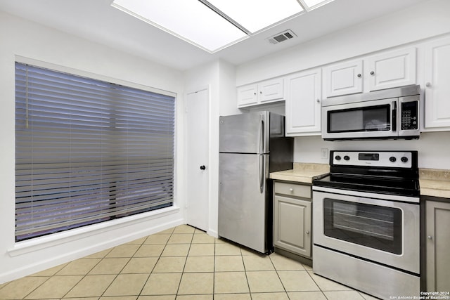 kitchen with light tile patterned floors, stainless steel appliances, and white cabinetry