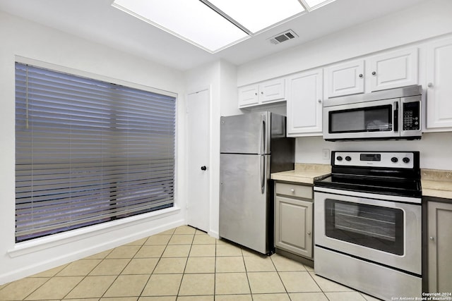 kitchen with light tile patterned floors, stainless steel appliances, light countertops, visible vents, and white cabinetry