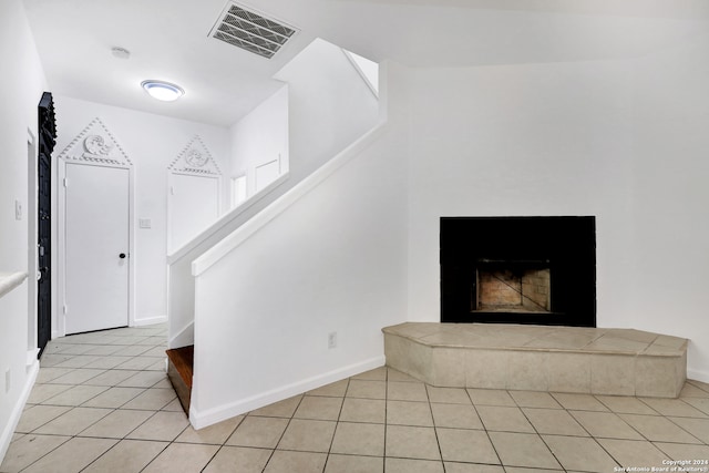 stairway featuring light tile patterned flooring and a fireplace