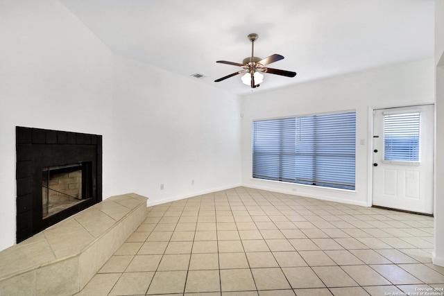 unfurnished living room featuring ceiling fan, light tile patterned floors, a tile fireplace, visible vents, and baseboards