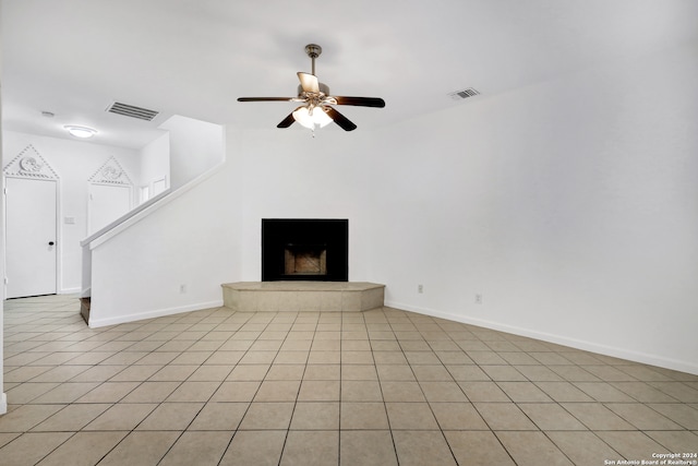 unfurnished living room with a fireplace, light tile patterned floors, and ceiling fan