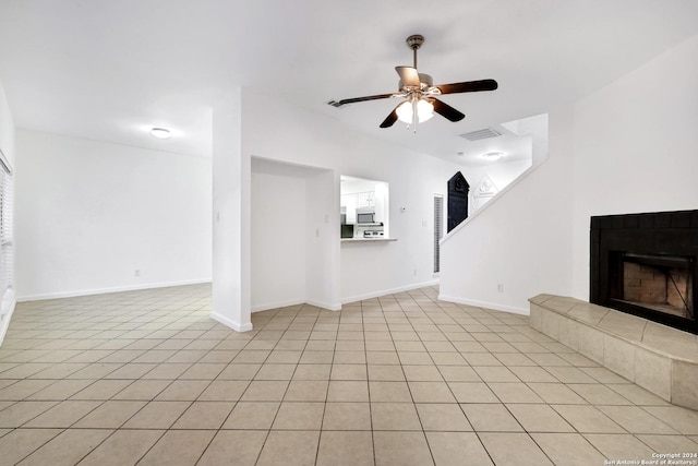 unfurnished living room with a ceiling fan, baseboards, visible vents, and a tiled fireplace