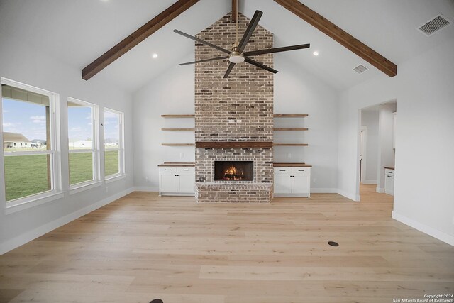 unfurnished living room with high vaulted ceiling, light wood-style flooring, visible vents, a ceiling fan, and beam ceiling