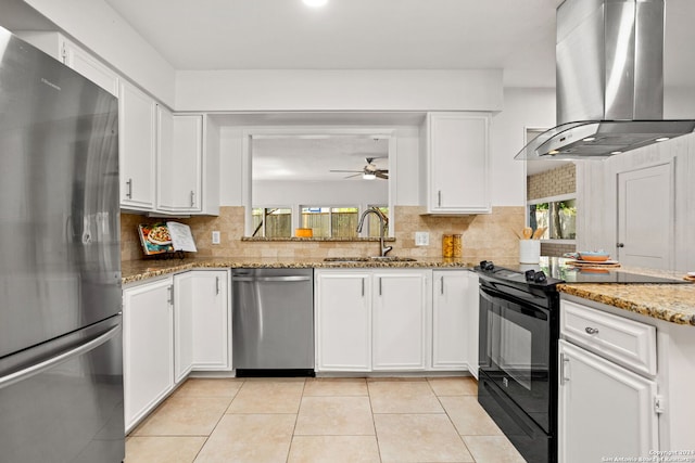 kitchen featuring appliances with stainless steel finishes, wall chimney range hood, sink, and a wealth of natural light