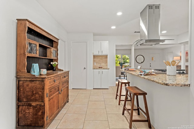 kitchen featuring white cabinets, light stone countertops, ventilation hood, light tile patterned flooring, and tasteful backsplash