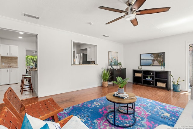 living room featuring ceiling fan, light wood-type flooring, and ornamental molding