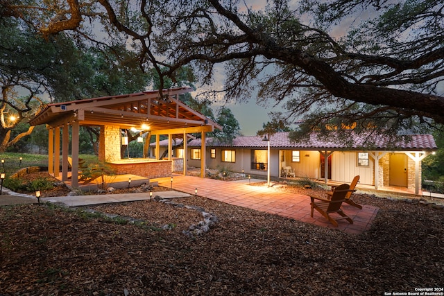 back house at dusk featuring a patio area