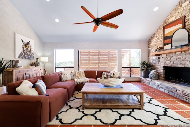 living room featuring vaulted ceiling, ceiling fan, light tile patterned floors, and a stone fireplace