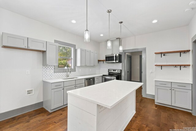 kitchen featuring decorative backsplash, dark hardwood / wood-style floors, pendant lighting, stainless steel appliances, and sink