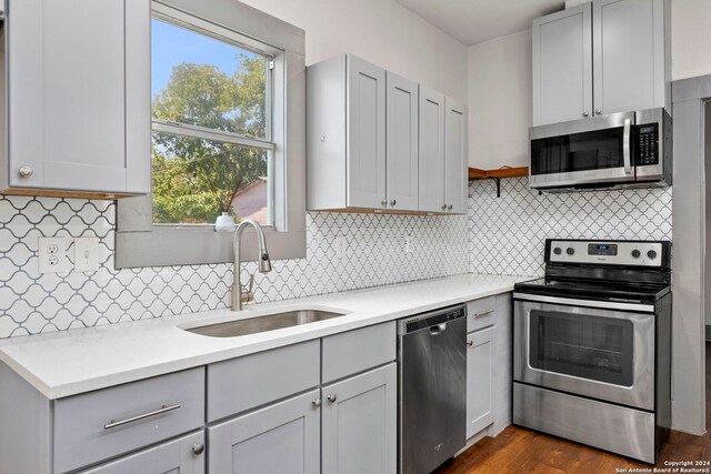 kitchen featuring appliances with stainless steel finishes, tasteful backsplash, dark wood-type flooring, and sink