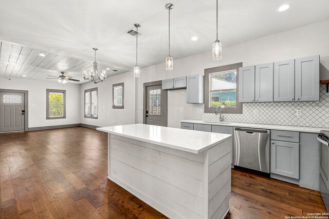 kitchen with dark hardwood / wood-style floors, hanging light fixtures, backsplash, stainless steel dishwasher, and a center island