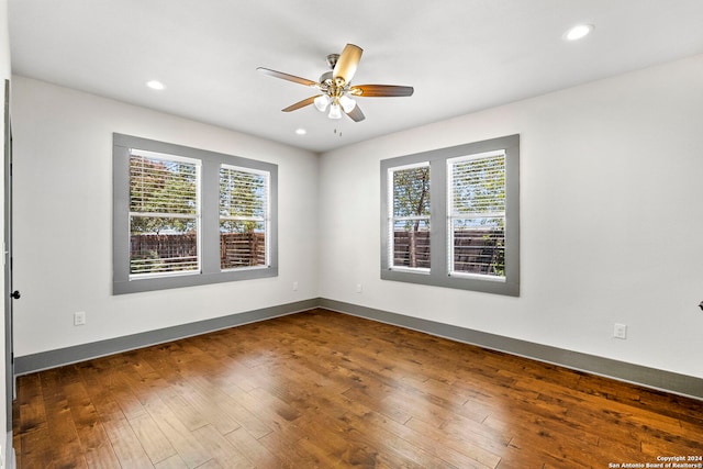 spare room featuring ceiling fan, hardwood / wood-style flooring, and a healthy amount of sunlight