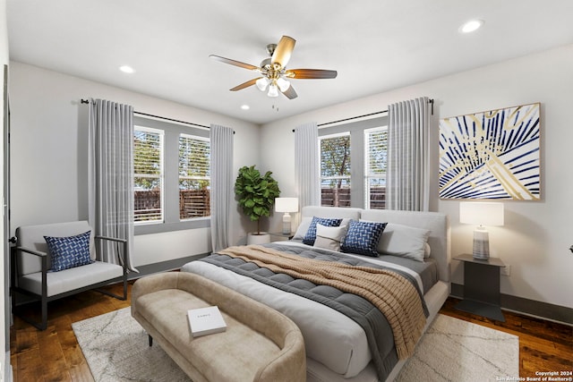 bedroom with ceiling fan, dark wood-type flooring, and multiple windows