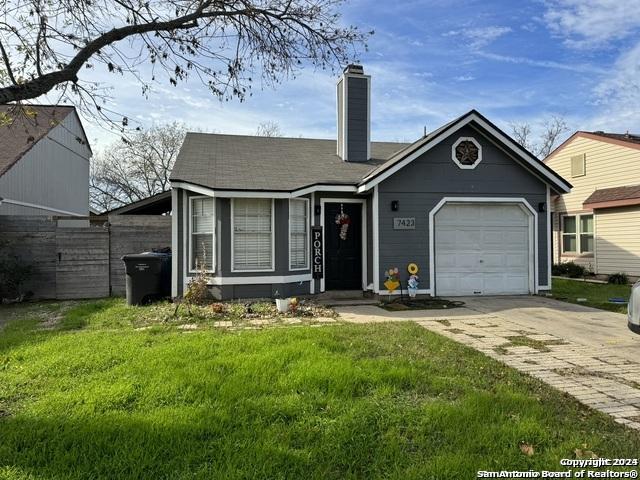 view of front of house featuring a front lawn, fence, concrete driveway, a garage, and a chimney