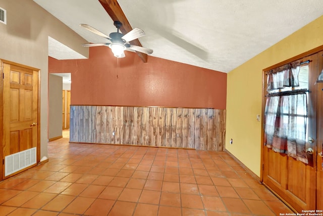 unfurnished room with ceiling fan, light tile patterned floors, vaulted ceiling, and a textured ceiling