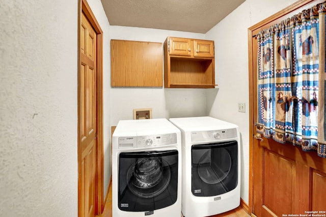 washroom with light wood-type flooring, washing machine and dryer, a textured ceiling, and cabinets