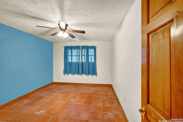 tiled empty room featuring ceiling fan and a textured ceiling