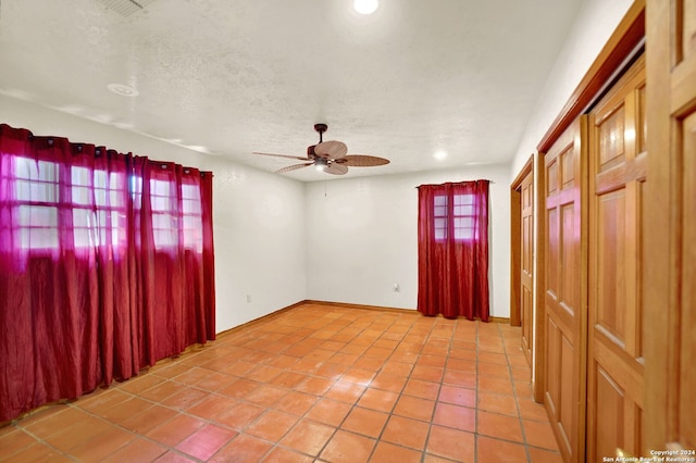 tiled spare room with ceiling fan and a textured ceiling