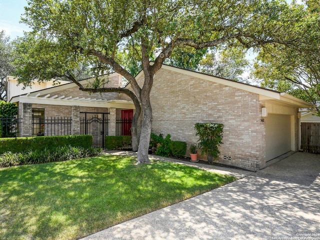 view of front of property featuring driveway, brick siding, a front lawn, and fence