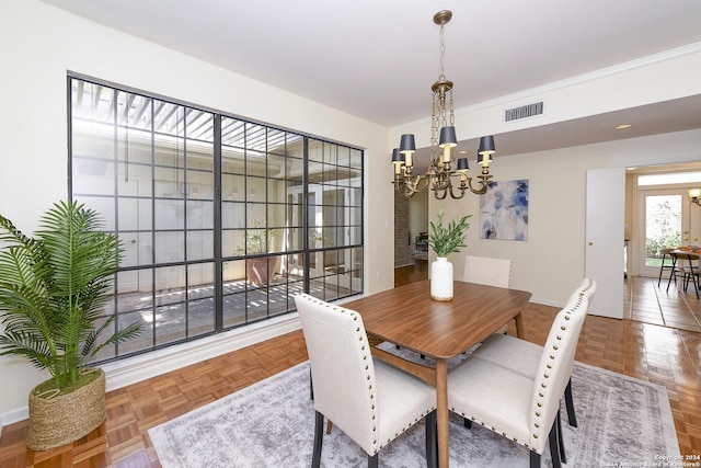 dining area featuring a chandelier, baseboards, visible vents, and crown molding