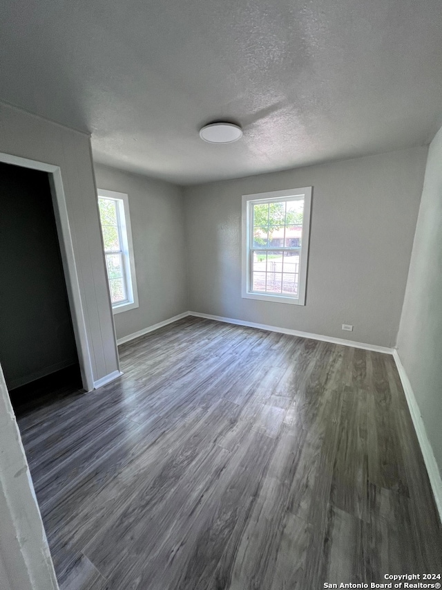 unfurnished room featuring a wealth of natural light, a textured ceiling, and hardwood / wood-style floors