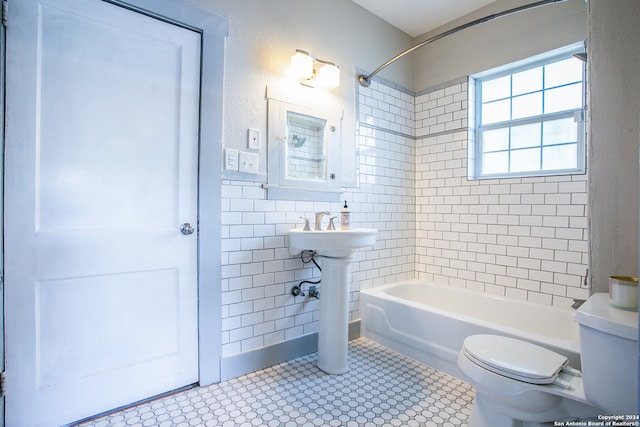 bathroom featuring tiled shower / bath combo, toilet, tile walls, and tile patterned flooring