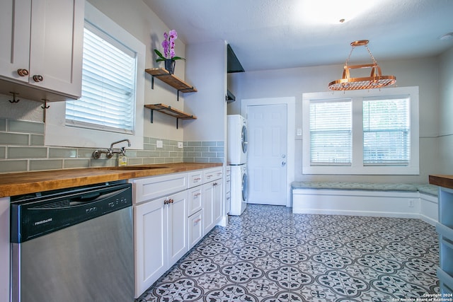 kitchen featuring white cabinets, dishwasher, stacked washer and dryer, tasteful backsplash, and butcher block counters