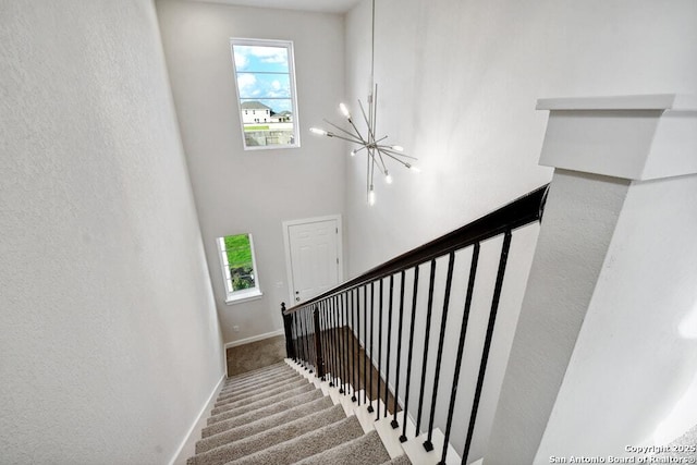 stairs featuring a chandelier and carpet