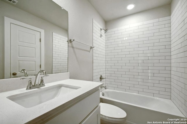 full bathroom with vanity, tiled shower / bath combo, and toilet