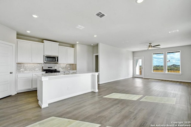 kitchen with white cabinetry, backsplash, a kitchen island with sink, and stainless steel appliances