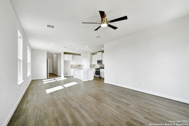 unfurnished living room with sink, hardwood / wood-style flooring, and ceiling fan