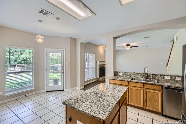 kitchen with ceiling fan, stainless steel dishwasher, light tile patterned floors, a kitchen island, and sink