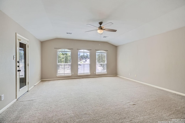 empty room featuring light carpet, baseboards, visible vents, and vaulted ceiling