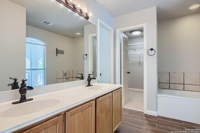 bathroom featuring double sink vanity, a tub, and wood-type flooring