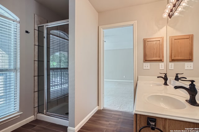 bathroom featuring a shower with shower door, dual bowl vanity, and hardwood / wood-style floors