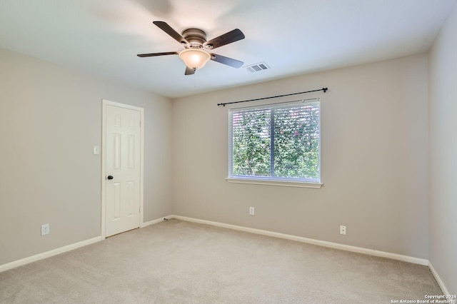 spare room featuring a ceiling fan, visible vents, light carpet, and baseboards