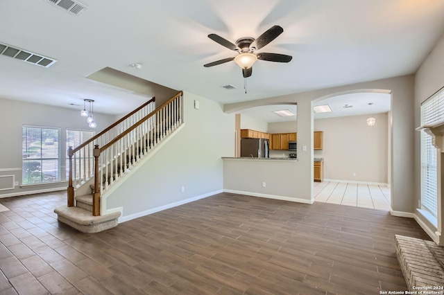 unfurnished living room with stairway, visible vents, and wood finished floors