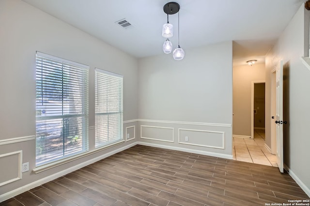 unfurnished room featuring a healthy amount of sunlight, visible vents, and wood finished floors