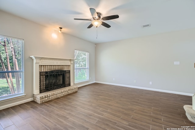 unfurnished living room with ceiling fan, wood-type flooring, and a brick fireplace