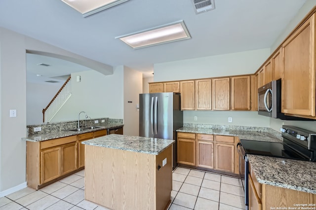 kitchen featuring light tile patterned floors, stainless steel appliances, a kitchen island, and light stone countertops