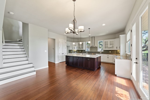 kitchen featuring dark wood-type flooring, a center island, decorative backsplash, and decorative light fixtures