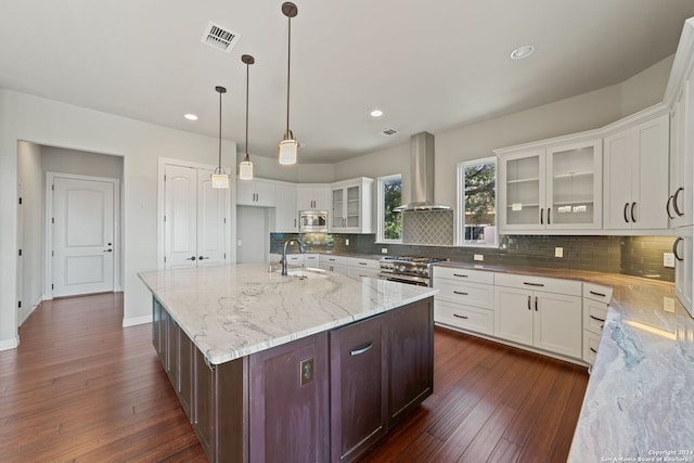 kitchen featuring dark hardwood / wood-style floors, stainless steel appliances, white cabinetry, and wall chimney exhaust hood