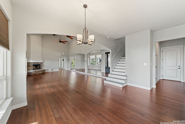 unfurnished living room featuring ceiling fan with notable chandelier, a fireplace, dark hardwood / wood-style flooring, and a high ceiling