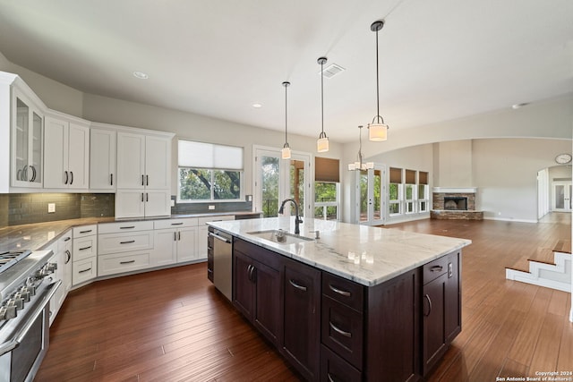 kitchen with a stone fireplace, appliances with stainless steel finishes, backsplash, sink, and dark hardwood / wood-style floors