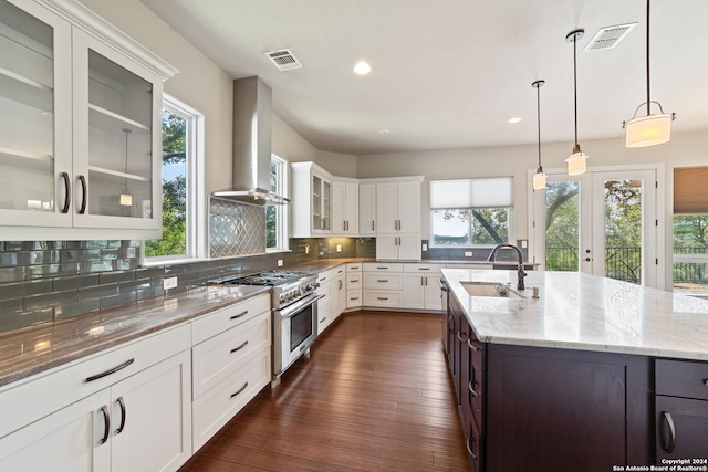 kitchen featuring dark hardwood / wood-style flooring, decorative backsplash, white cabinets, high end range, and wall chimney range hood