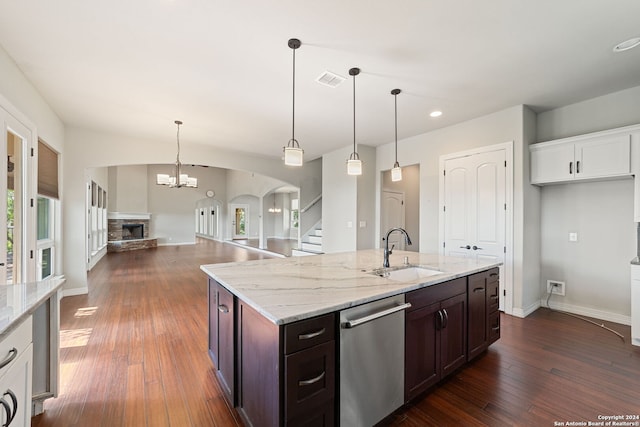 kitchen featuring dark wood-type flooring, light stone countertops, sink, stainless steel dishwasher, and a fireplace