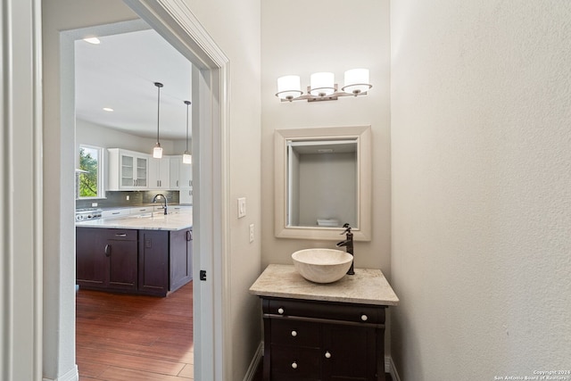 bathroom with a notable chandelier, tasteful backsplash, vanity, and wood-type flooring