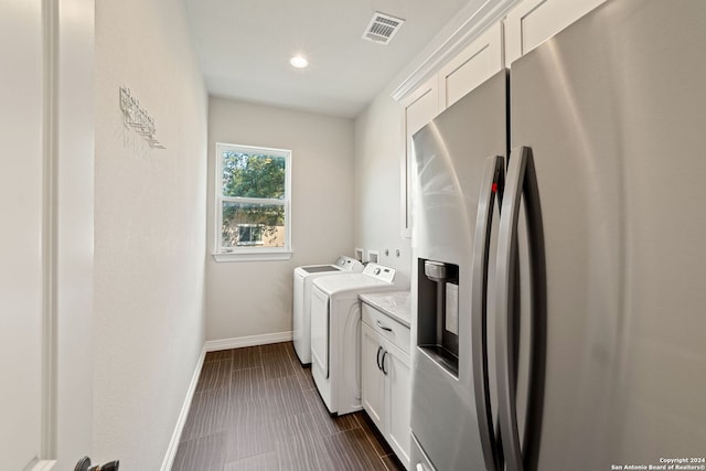 clothes washing area featuring cabinets, dark tile patterned floors, and washer and dryer